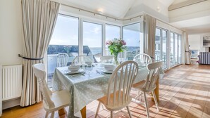 Un comedor con una mesa para cuatro, ventanas amplias y vista al mar.