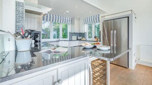 Una cocina moderna con una isla grande, electrodomésticos de acero inoxidable y vistas al exterior.