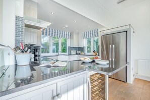 A modern kitchen with a large island, stainless steel appliances, and a view of the outdoors. - 5 Bed in Rock (oc-u22448) (Rock)