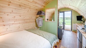 Une chambre confortable avec un lit, un miroir, une petite table avec un téléviseur et une vue sur l’extérieur.