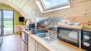 Une cuisine moderne équipée d’un four encastré, d’un évier et d’une fenêtre située au-dessus du plan de travail.