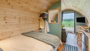 Een gezellige kamer met een bed, bureau, televisie en uitzicht op de omgeving.