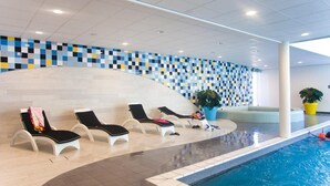 Un espace aménagé au bord de la piscine, avec des chaises longues, un mur carrelé et une piscine.
