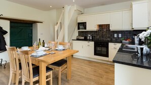 Una cucina moderna con mobili bianchi, un tavolo da pranzo in legno e una scala che conduce a un piano superiore.