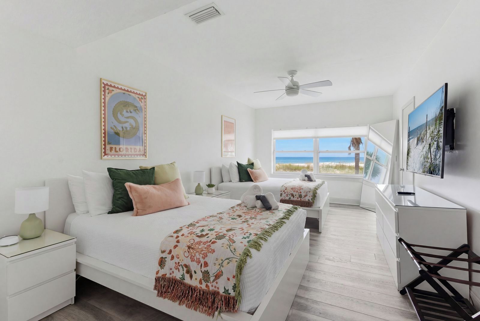 Une chambre d’hôtel avec un lit, un bureau, une télévision et une fenêtre donnant sur la plage.