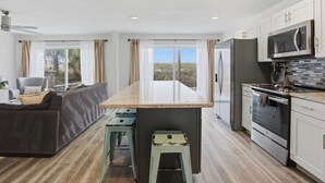 A modern kitchen with a central island, built-in appliances, and a view to the outside. - Be A Nomad | 2BR Beach Apartment | 1-Min Walk to Sand | Sleeps 4 (Jacksonville Beach)