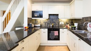 Een moderne keuken met witte kasten, een zwart aanrecht en een magnetron.