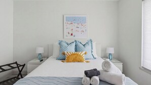 Hotelkamer met een bed, twee nachtkastjes, een stoel, een lijst met een afbeelding aan de muur en een raam met zonwering.