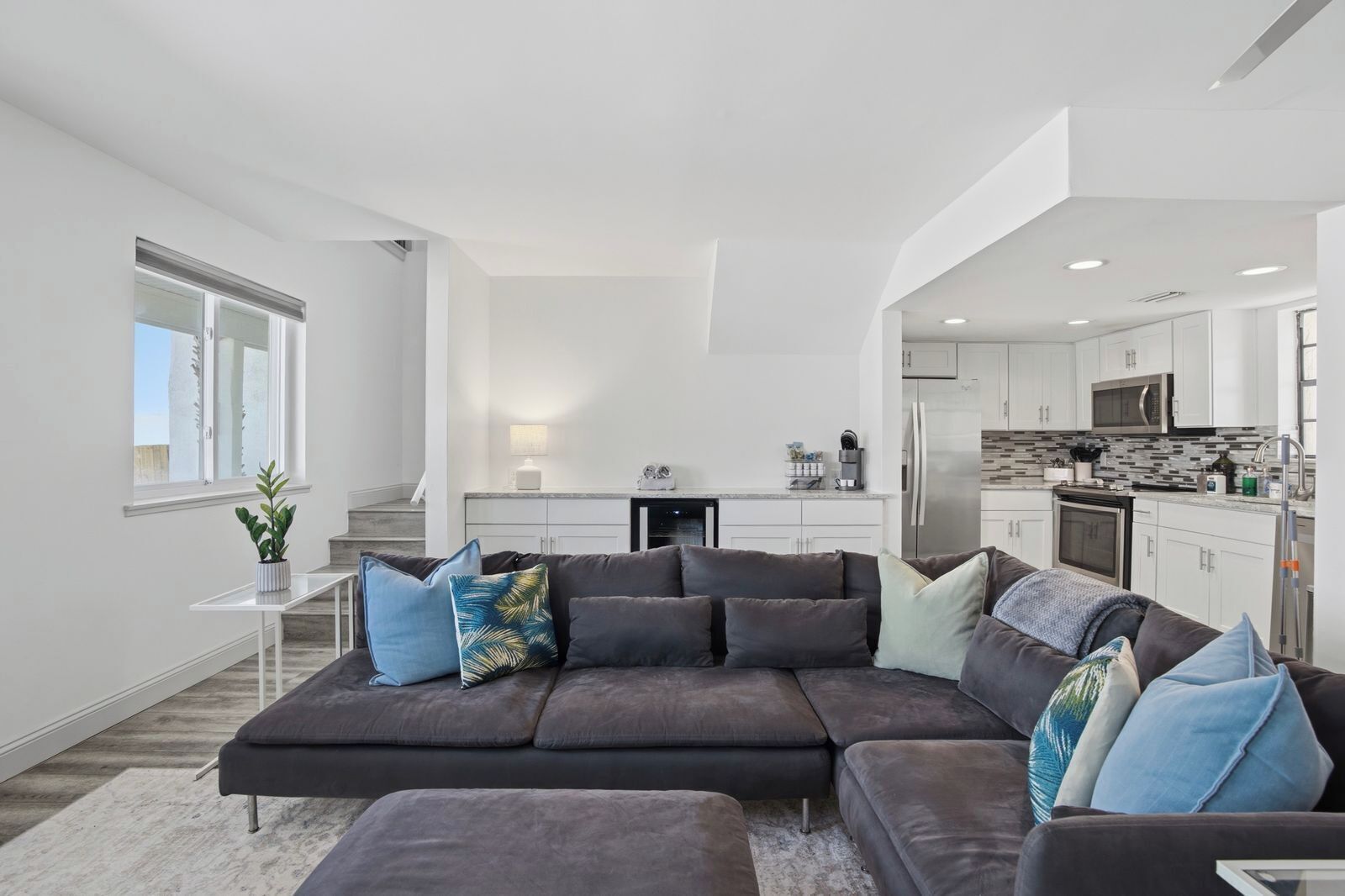 A modern living room with a sectional sofa, a small table, and a kitchen in the background.