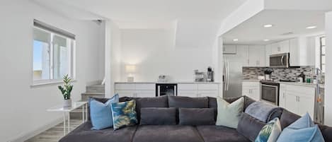 A modern living room with a sectional sofa, a small table, and a kitchen in the background.