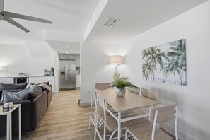 Eine moderne Küche mit Kühlschrank, eine Essecke mit Tisch und Stühlen und ein Deckenventilator.