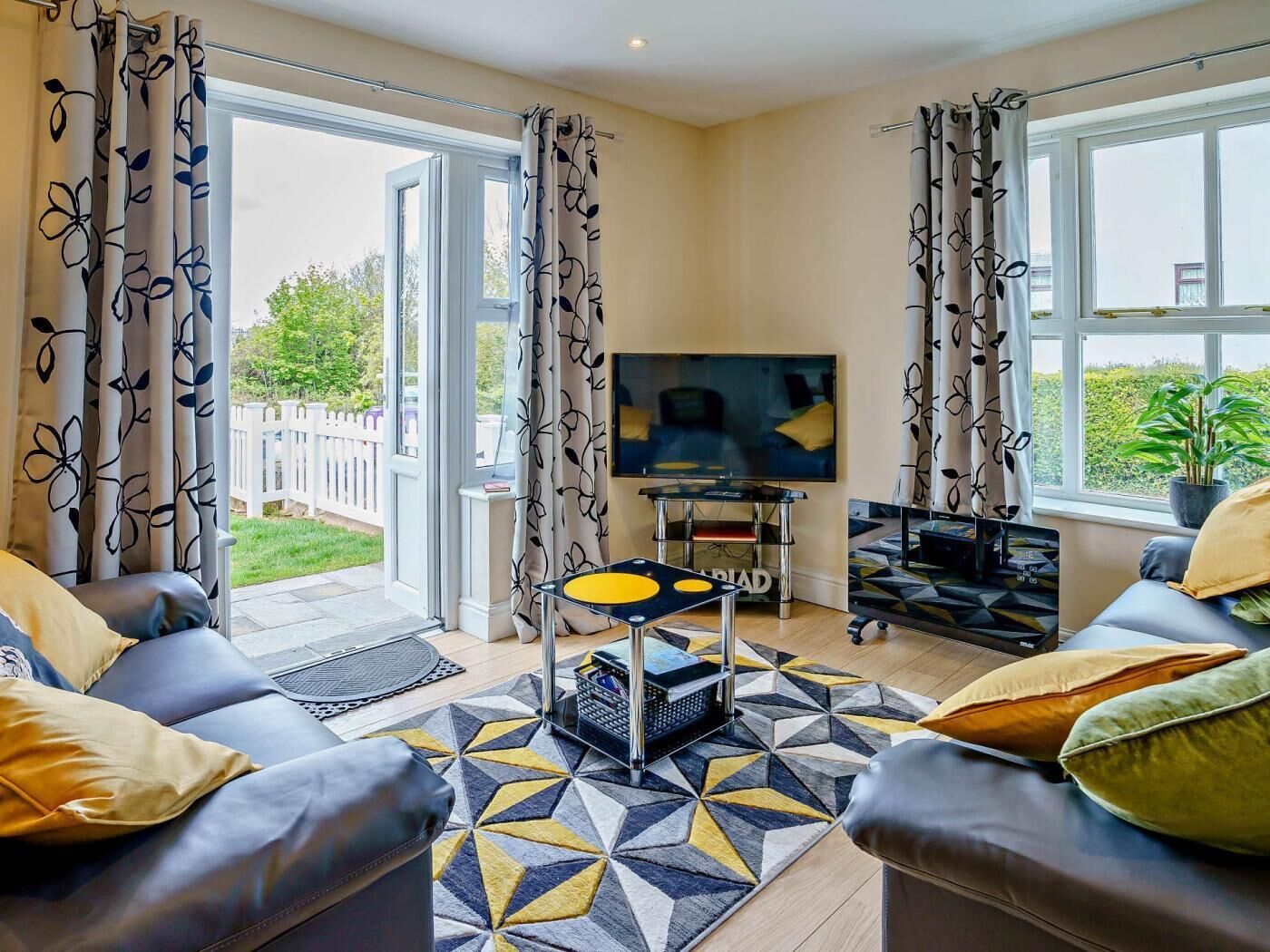 Un salon avec un canapé, une table basse, un téléviseur et un tapis à motifs.