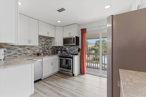 Une cuisine moderne avec des meubles blancs, un four à micro-ondes, un four traditionnel et un plancher en bois.