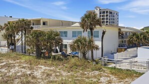 A coastal hotel with multiple buildings, palm trees, and a sandy foreground. - Be A Nomad | 3 Bed 3 Bath | 1 Min to Jacksonville Beach | Sleeps 6 (Jacksonville Beach)