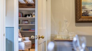 Ein Zimmer mit einer zur Wohnbereich führenden Tür, einem Karaffenglas auf einer Ablage und einem gerahmten Gemälde an der Wand.