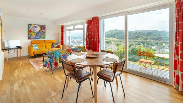 A modern living room with a dining area, large windows, and a view of the countryside. - 2 Bed in Ambleside (oc-lr111) (Ambleside)