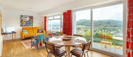 Una sala de estar moderna con comedor, ventanas amplias y vistas al campo.