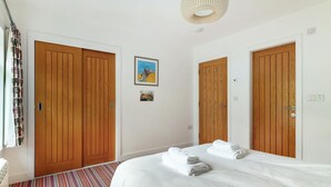 A hotel room with two wooden doors, a bed with white linens, a striped carpet, and a ceiling light fixture. - 2 Bed in Ambleside (oc-lr111) (Ambleside)