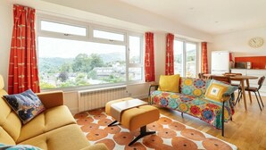 A room with a sofa, a chair, a table, and a view through large windows. - 2 Bed in Ambleside (oc-lr111) (Ambleside)
