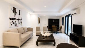 A modern living room with a sofa, armchairs, a coffee table, and a TV. - Luxury Apartment in Ain Zaghouan (Ain Zaghouan)