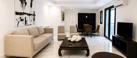 A modern living room with a sofa, armchairs, a coffee table, and a TV.