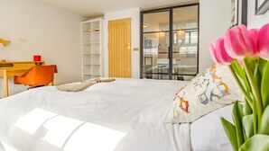 Ein Schlafzimmer mit Bett, Schreibtisch, Stuhl, Kleiderschrank und einer Schiebetür zu einem Badezimmer.