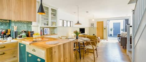 Una cocina moderna con armarios de madera, una isla central y una zona de comedor con mesa y sillas.