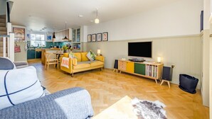 Ein Wohnzimmer mit einer Couch, einem Fernseher und einem Bücherregal.