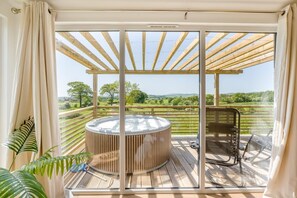 A balcony with a hot tub, wooden deck, and a view of a green landscape. - 1 Bed in Dalry (oc-b43281) (Dalry)