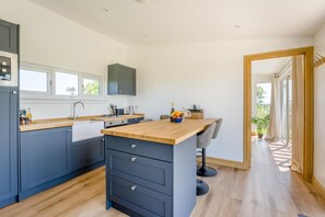 A modern kitchen with a wooden island, dark cabinetry, and a large window.