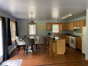 A spacious kitchen with wooden cabinets, a dining area with a table and chairs, and a central island with a sink. - 2bedroom home, lake access, snowmobile trail access, ac/fire place, Indian Lake (Indian lake)