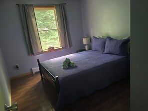Een slaapkamer met een bed, een raam, een nachtkastje en een lamp.
