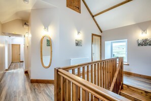 Ein Flur mit einer Holztreppe, einem Spiegel und einer Tür zu einem Zimmer mit Blick.