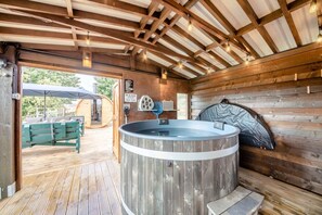 Ein Holzblockbau-Innenraum mit Whirlpool, Holzbalken und einer Bank vor der Tür.