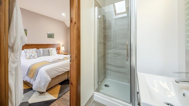 Een hotelkamer met een bed, een douche in een glazen cabine en een witte badkamer.