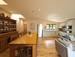 A modern kitchen with a dining area, wooden furniture, and a grey sofa. - 3 Bed in Lambourn (oc-w42717) (Sheepdrove)