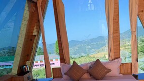 Una habitación de madera con una cama, almohadas y vistas a un paisaje montañoso.