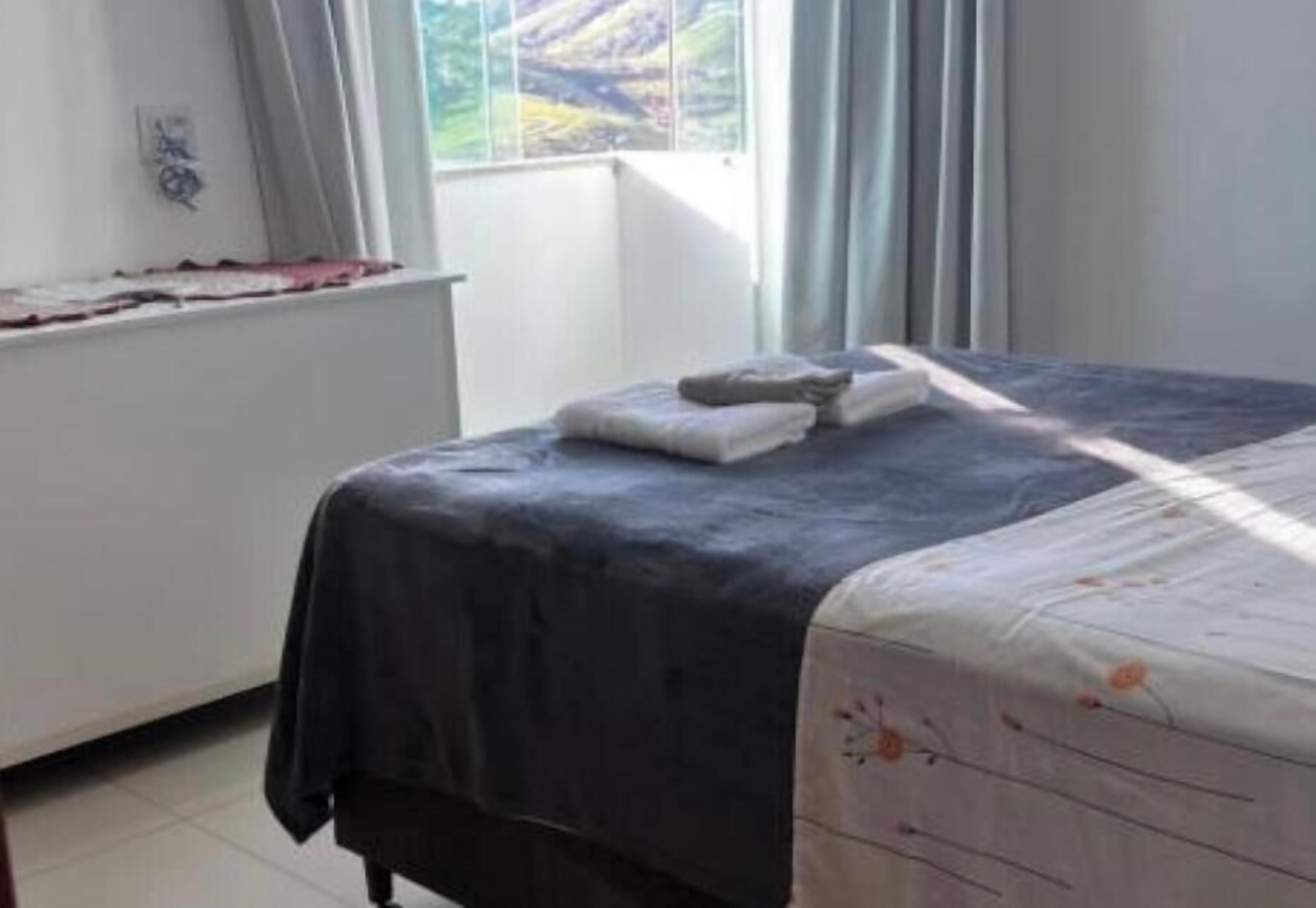 Ein Schlafzimmer mit einem Bett, einem Fenster mit Vorhängen und einer Heizung.