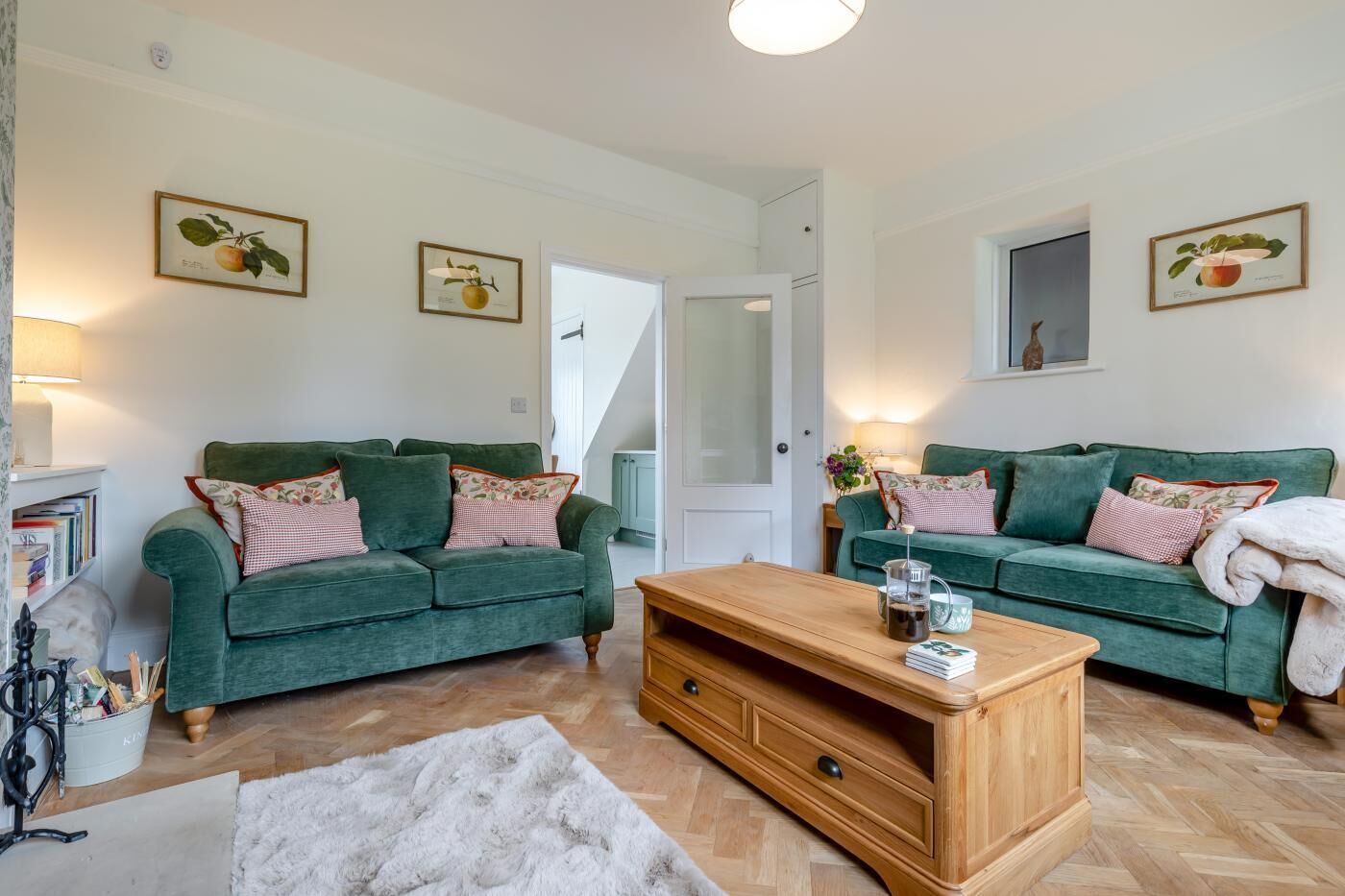 A living room with two green sofas, a wooden coffee table, and a white fluffy rug.