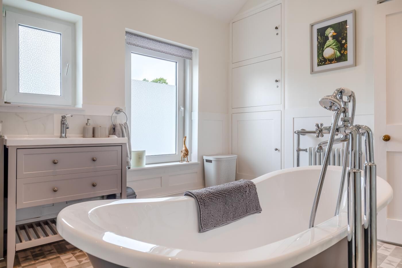 A bathroom with a bathtub, a window, a sink, and a shower.