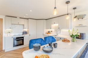 A modern kitchen with white cabinetry, a marble countertop, and a central island with seating. - 1 Bed in Low Row (oc-c43317) (Low Row)