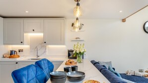 A modern kitchen with a marble countertop, a blue upholstered chair, and a dining area with a blue sofa. - 1 Bed in Low Row (oc-c43317) (Low Row)