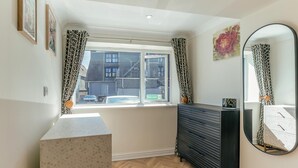 Ein Zimmer mit einem großen Fenster, einem Schminktisch, einem Spiegel und einer Wand mit Muster.