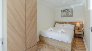 Ein Schlafzimmer mit Bett, Nachttisch, Lampe und Wandbild.