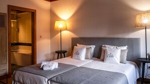 Une chambre d’hôtel comprenant un lit, deux lampes de chevet, une table ronde et un espace douche.