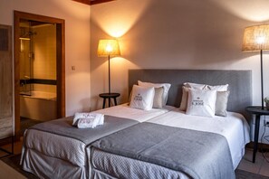 Een hotelkamer met een bed, twee bedlampen, een ronde tafel en een douchehoek.