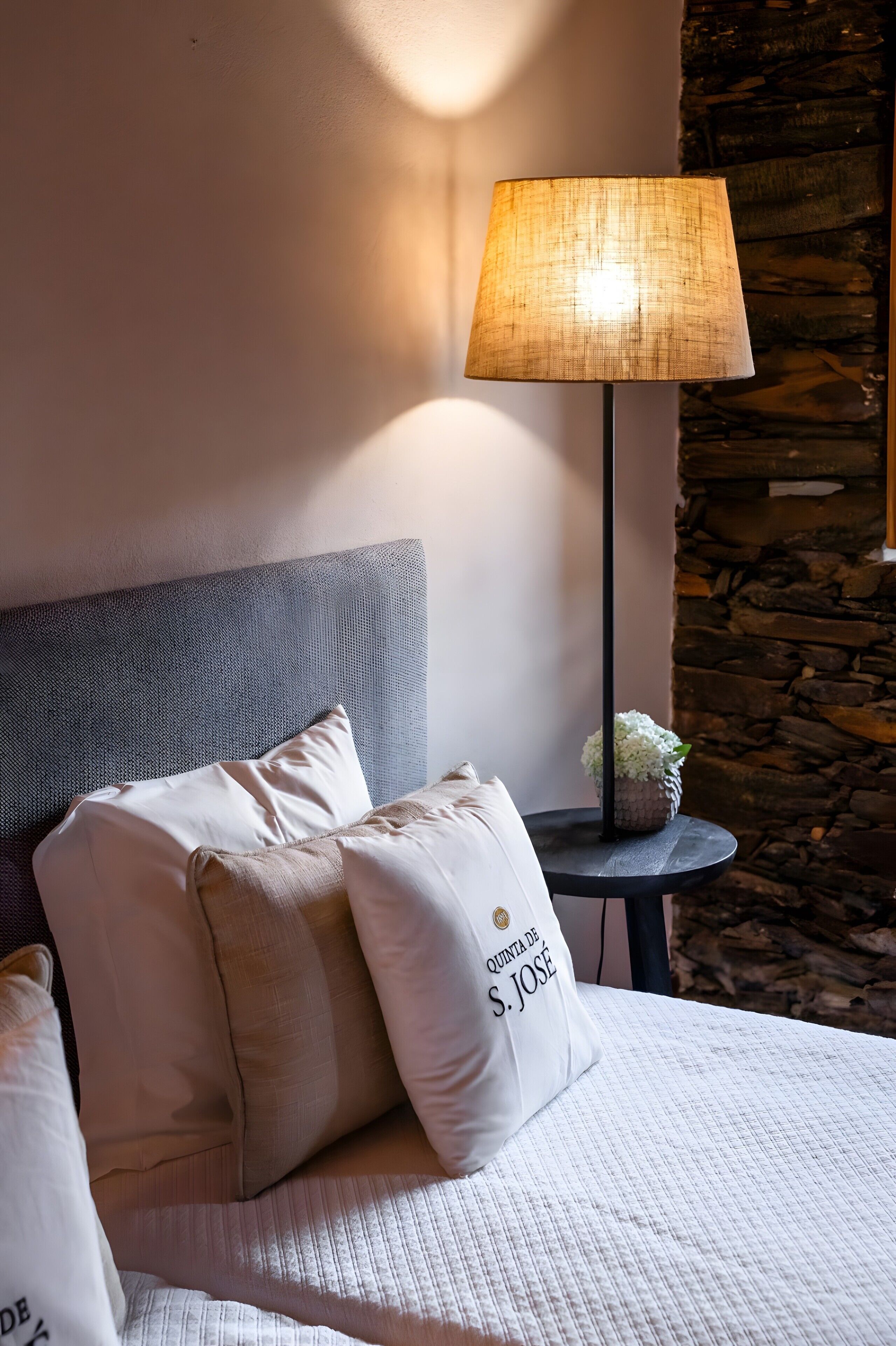 Un letto con cuscini, una lampada e un tavolino con una pianta.