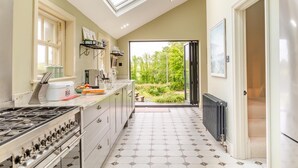 Une cuisine dotée d’une lucarne, offrant une vue sur la verdure et recouverte d’un carrelage.