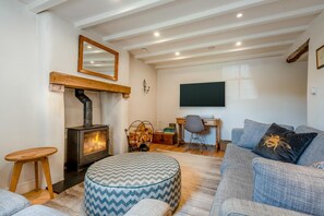 A cozy living room with a fireplace, a comfortable sofa, a desk with a chair, and a television. - 3 Bed in Skelton (oc-c42824) (Skelton)
