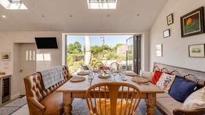 Un coin repas avec une table dressée pour quatre personnes, un canapé et un téléviseur fixé au mur.